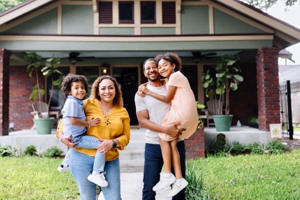 Family smiling in front of their rent-to-own home in Michigan